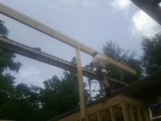 Carpenter setting a ridge beam over a new addition frame — Ice Dam Removal by Roofing Brothers in Collettsville