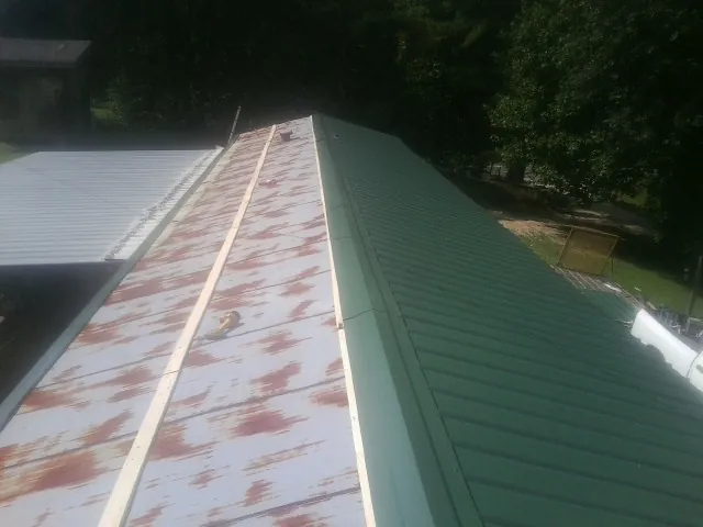 Old rusted panels beside newly installed green metal roofing — Wind Damage Roof Repair by Roofing Brothers in Collettsville