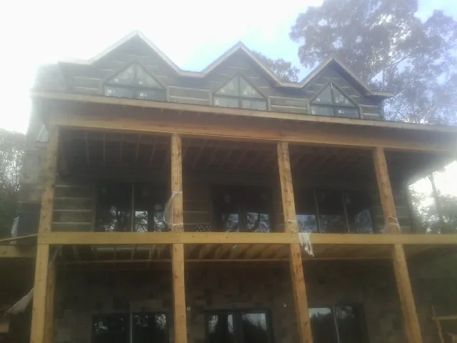 Dormers and porch framing on a large log home under construction — Roof Coating work by our crew in Collettsville