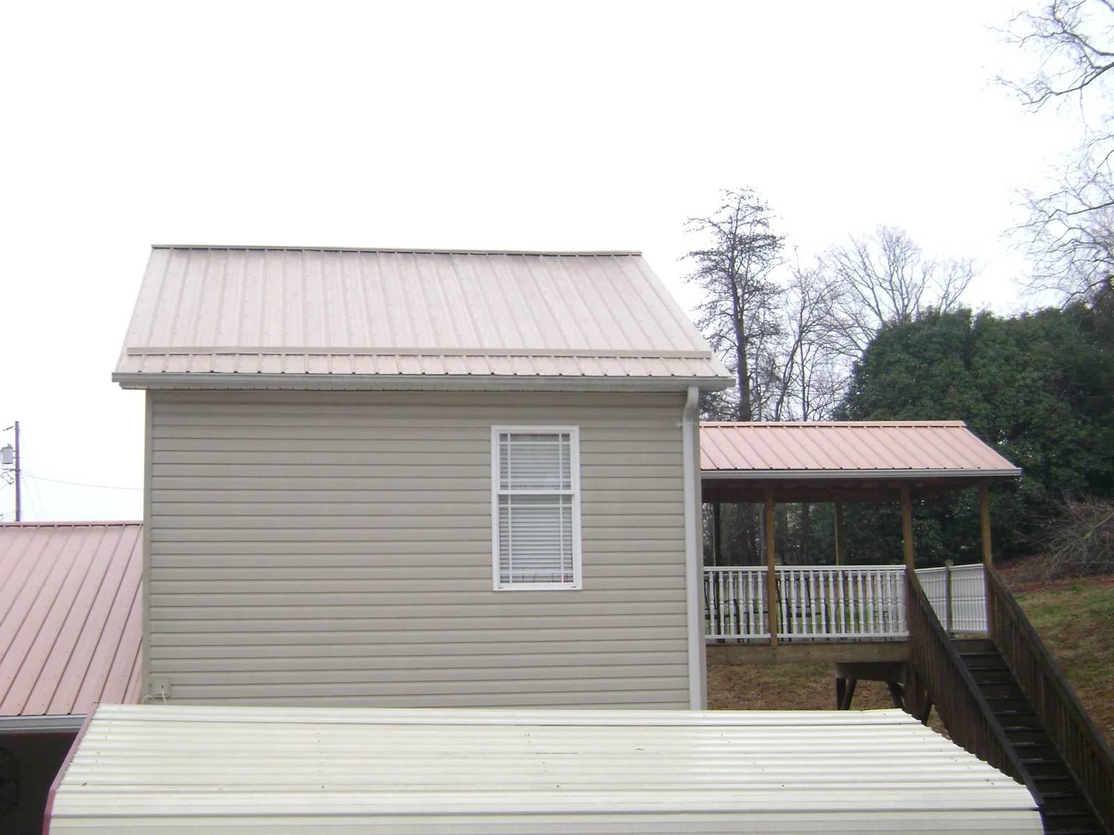 Tan metal roofs on a two story addition and attached porch, from a Roof Replacement job in Collettsville